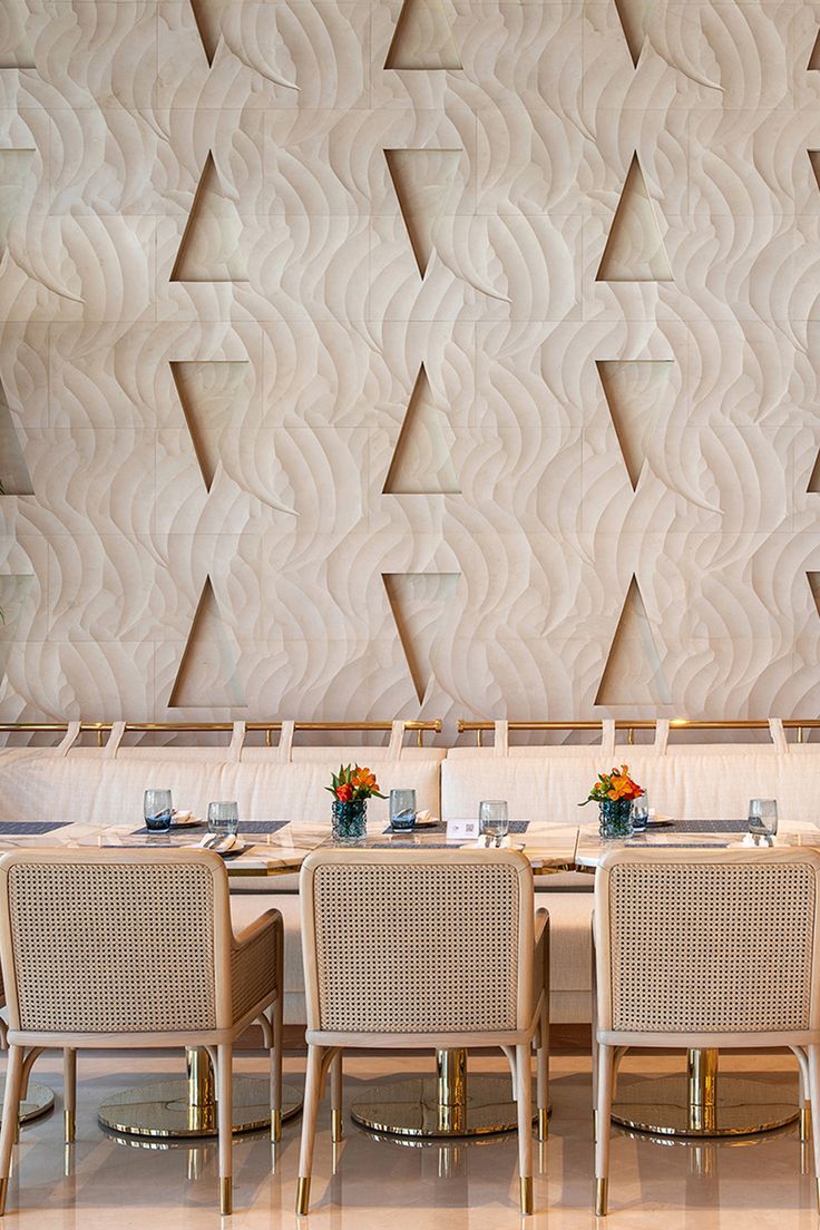 a dining room with tables and chairs in front of a wall made of geometric shapes