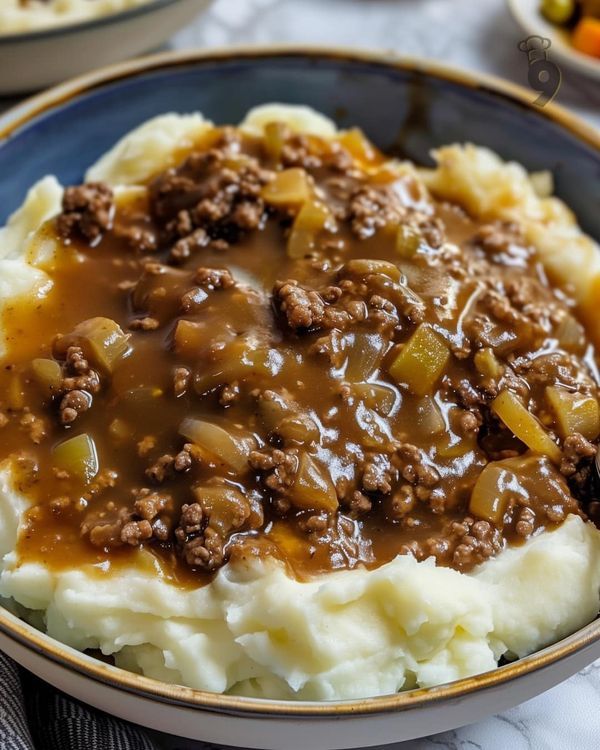 a bowl filled with mashed potatoes covered in ground beef and gravy on top