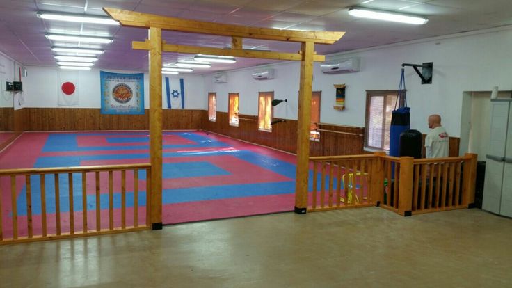 an indoor gym with pink and blue mats on the floor, two men standing in doorways