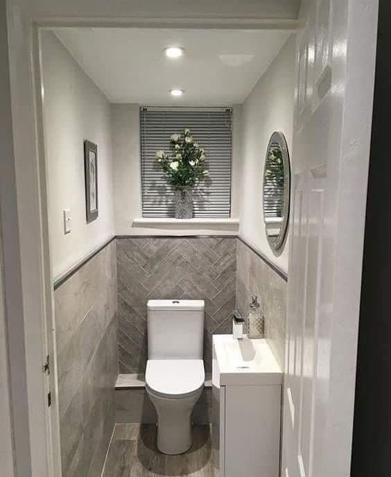 a white toilet sitting inside of a bathroom next to a sink under a mirror on the wall