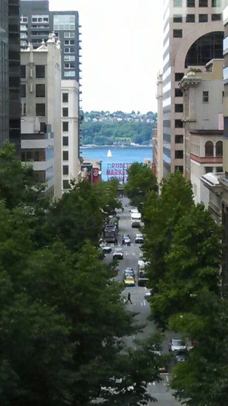 a city street filled with lots of traffic next to tall buildings and water in the distance