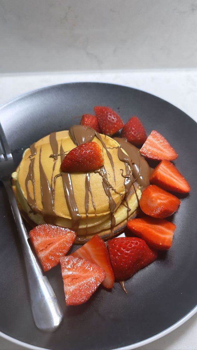 a pancake with strawberries and chocolate drizzled on top