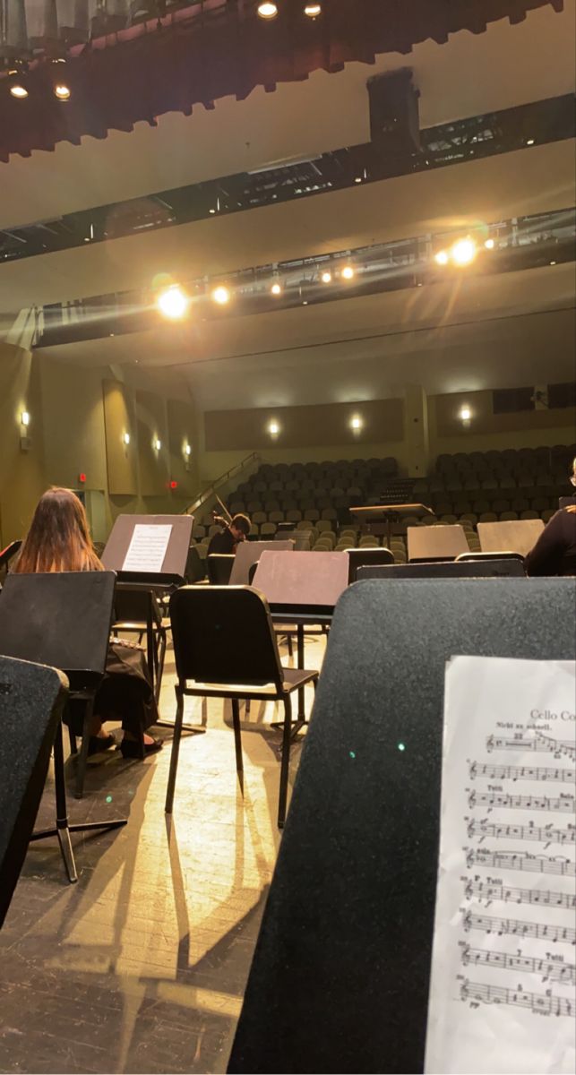 an empty auditorium filled with lots of chairs and sheet music sheets on the floor in front of them