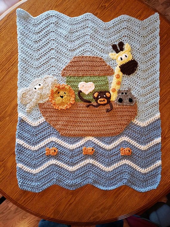 a crocheted rug with animals on it sitting on top of a wooden table