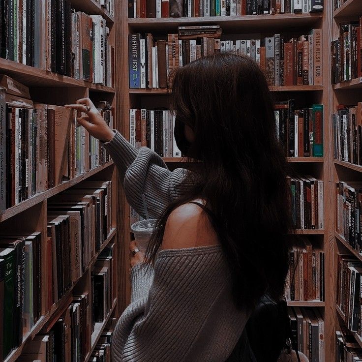 a woman standing in front of a book shelf filled with books