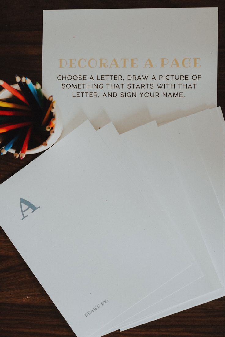 five pieces of paper sitting on top of a wooden table next to a bowl of crayons