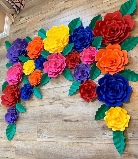 colorful paper flowers are arranged on the wall