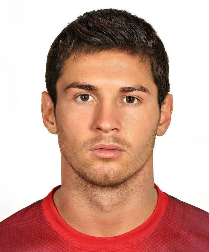 a close up of a soccer player wearing a red uniform and looking at the camera