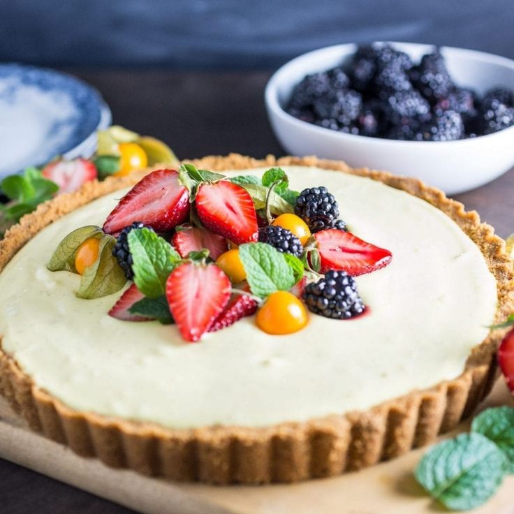 a cheesecake topped with fresh fruit on a cutting board