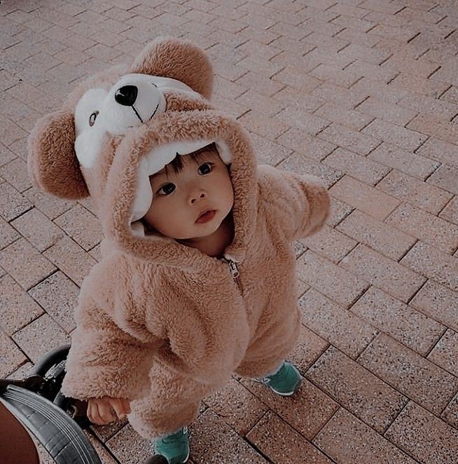 a small child in a teddy bear costume riding on a scooter with wheels