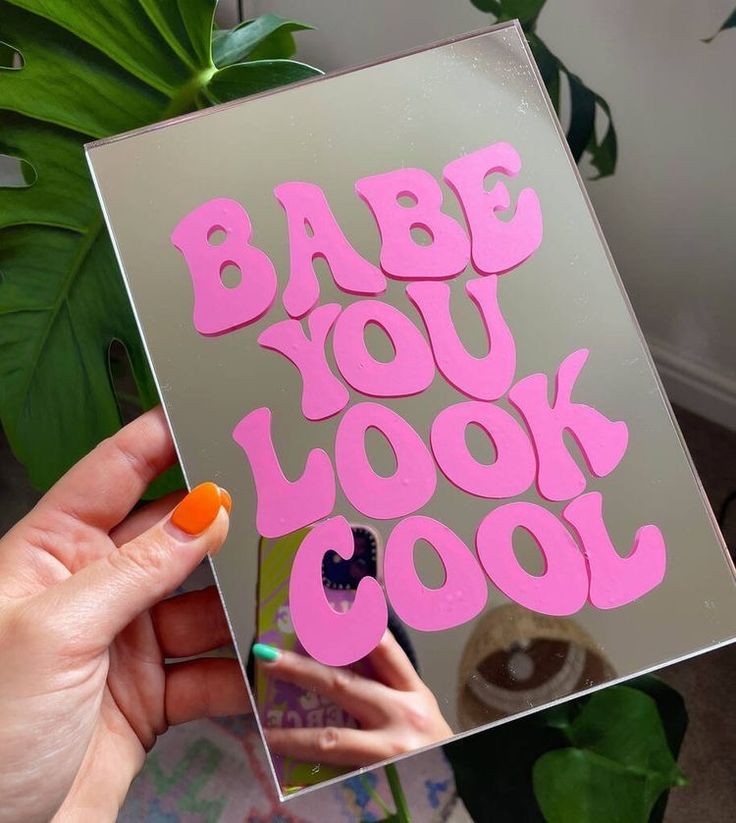 a person holding up a card with the words babe you look cool on it in pink