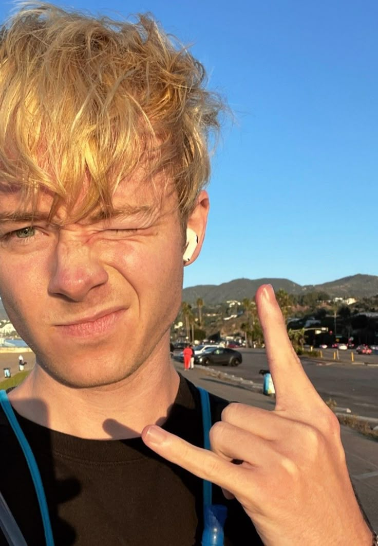 a young man with blonde hair and piercings making the middle finger sign for the camera