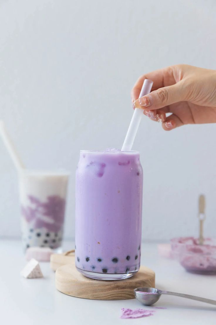 a person is holding a straw in a purple drink