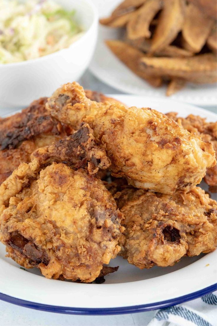 some fried food on a plate with coleslaw and potato wedges in the background