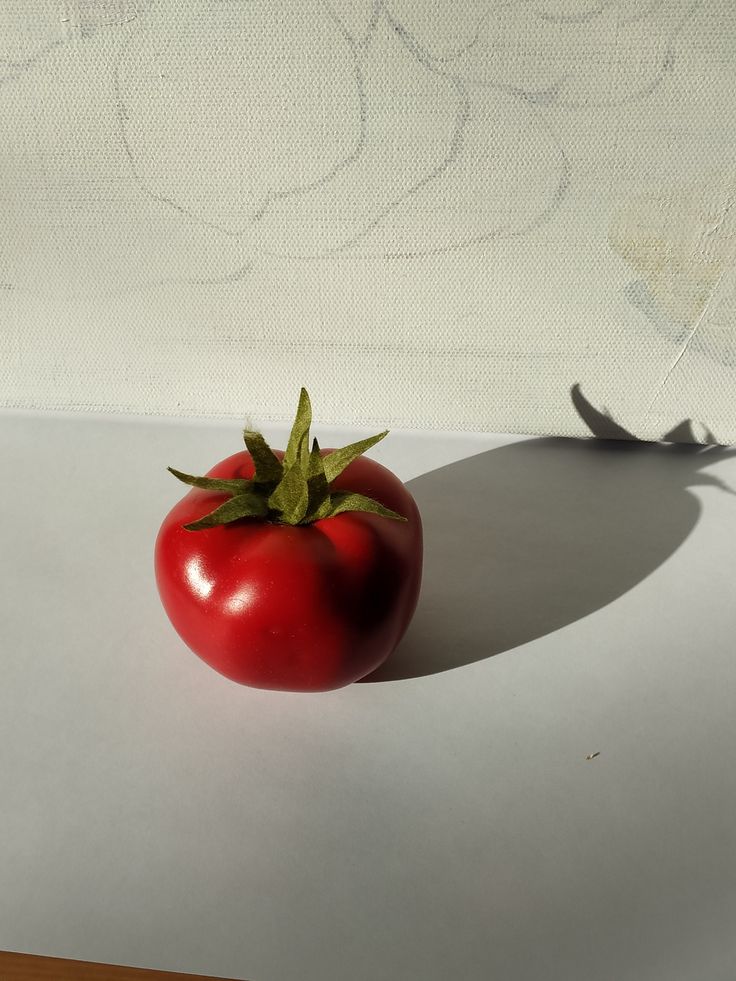 a red tomato sitting on top of a table