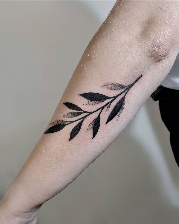 a black and white photo of a person's arm with a leaf tattoo on it