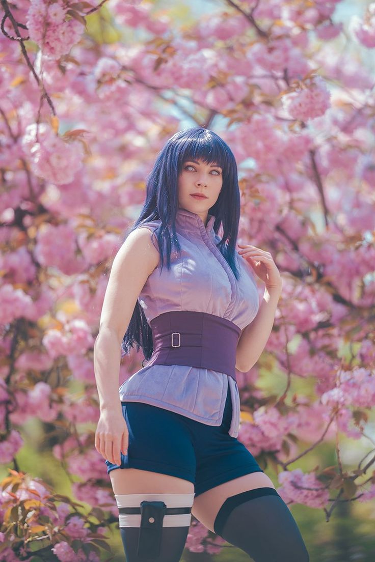 a woman with blue hair is posing in front of some pink flowers wearing knee high socks