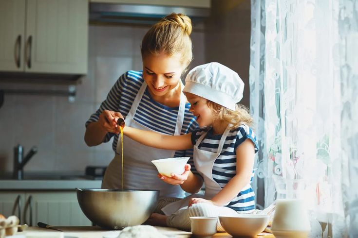 a mother and daughter cooking together in the kitchen