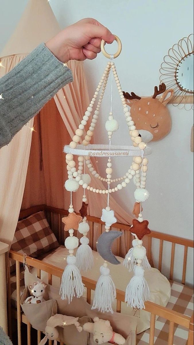 a baby crib with a teddy bear hanging from it's side and other toys in the background