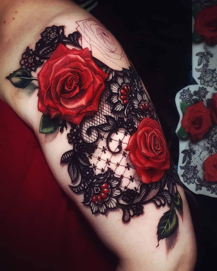 a woman's arm with red roses on it and lacework in the middle