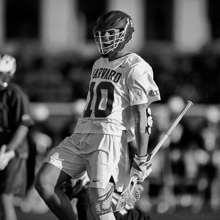 a black and white photo of a lacrosse player on the field with his helmet up