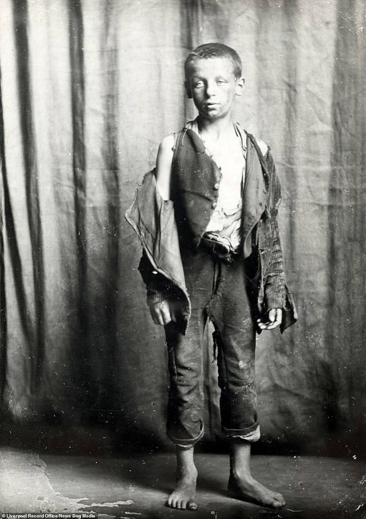 an old black and white photo of a young boy in overalls, standing with his hands on his hips