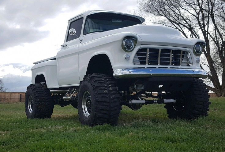 an old white truck parked in the grass