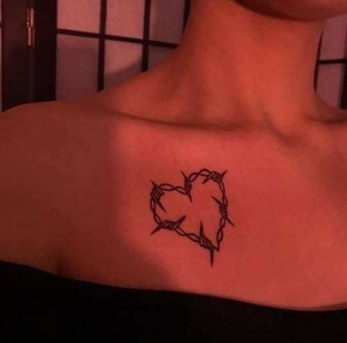 a woman with a tattoo on her shoulder that has barbed wire in the shape of a heart