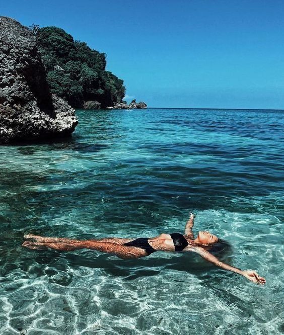 a woman is floating in the clear blue water