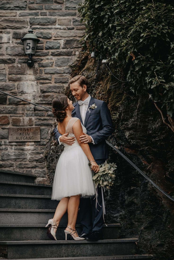 a bride and groom are standing on the stairs