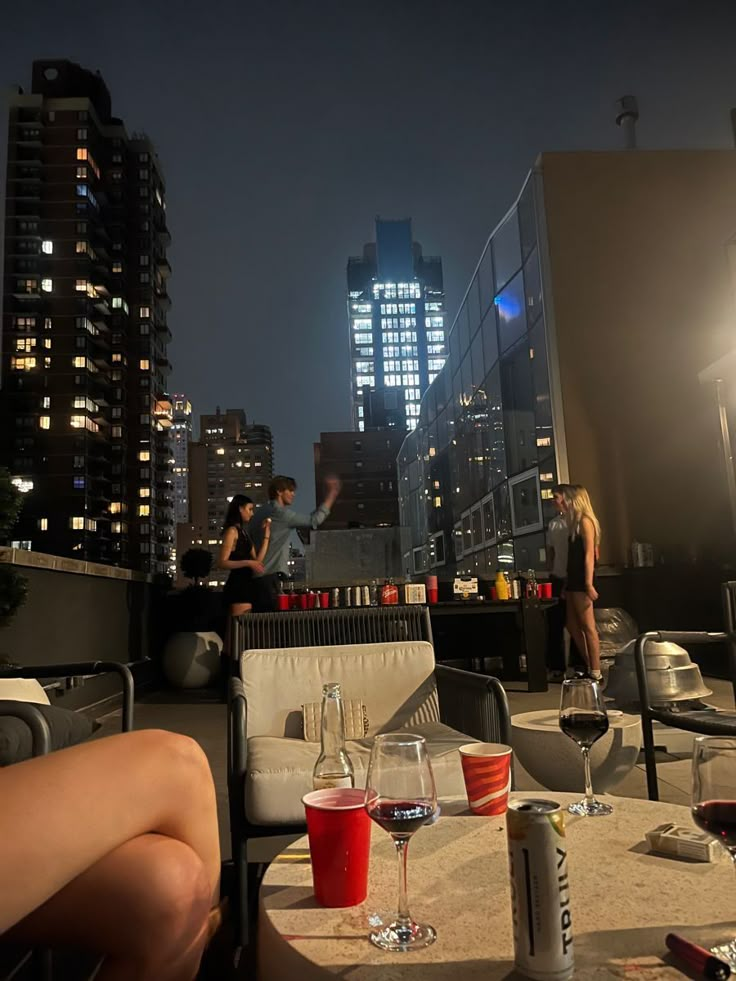 two people sitting at a table with wine glasses on it in front of the city skyline