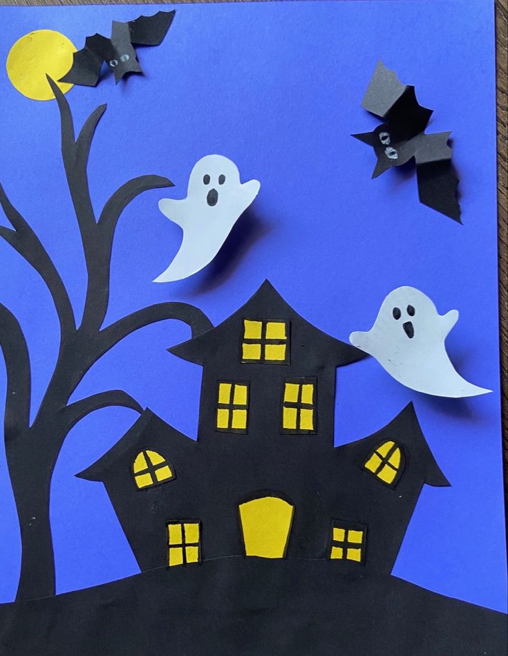 paper cut out of the shape of a house with bats flying over it and two ghost houses