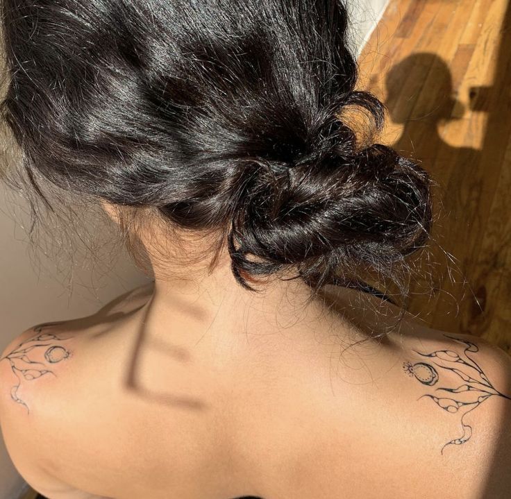 the back of a woman's head with tattoos on her upper arm and shoulder