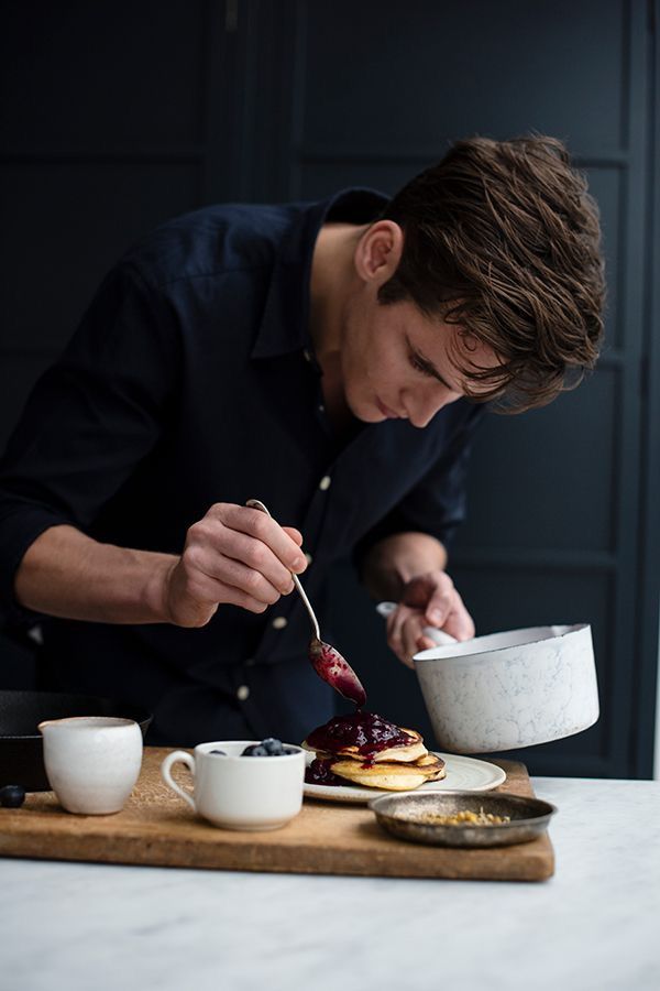 a man sitting at a table with food in front of him and looking down on his plate