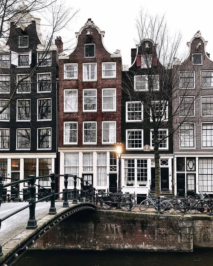 several buildings with bicycles parked on the side of them in front of a bridge and water