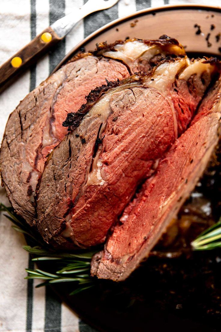 a piece of meat sitting on top of a pan covered in sauce and garnished with herbs