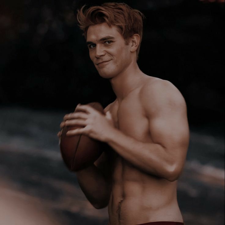 a man with no shirt holding a football