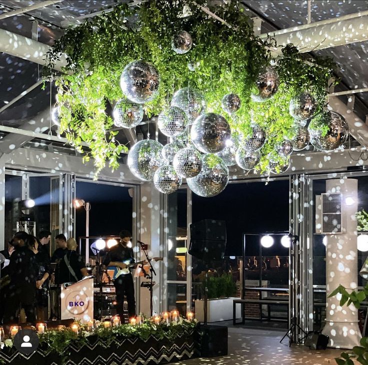 a room filled with lots of shiny balls and greenery hanging from the ceiling above