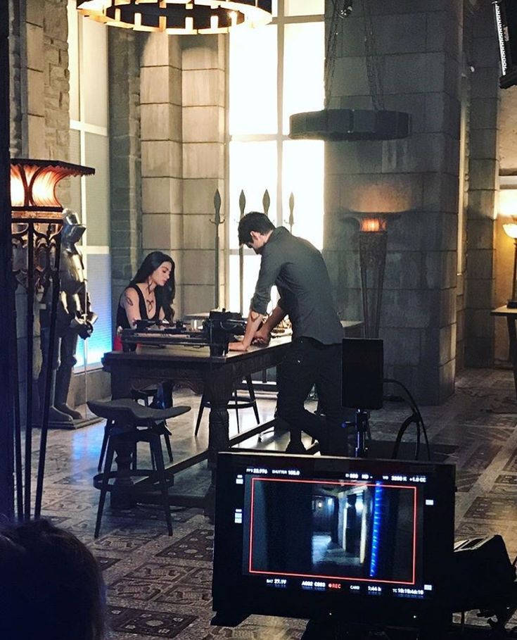 a man and woman standing next to each other in front of a table with a tv on it