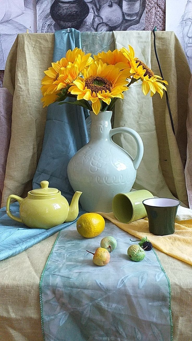 a table topped with a vase filled with sunflowers next to a tea pot