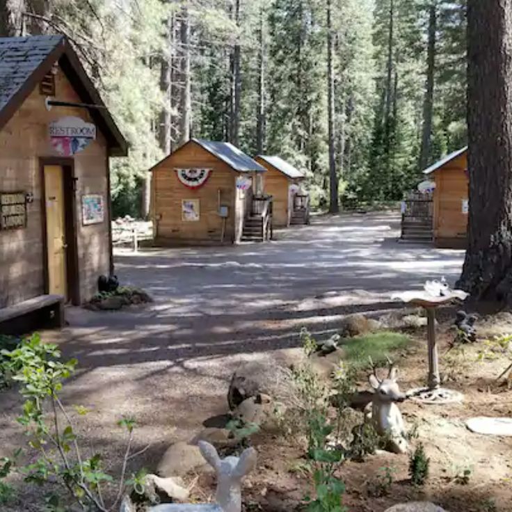 several small cabins in the woods with trees and rocks on the ground next to them