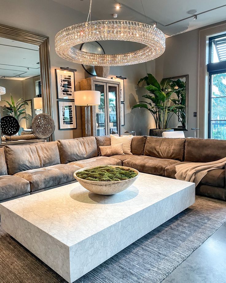 a living room with a couch, coffee table and chandelier hanging from the ceiling