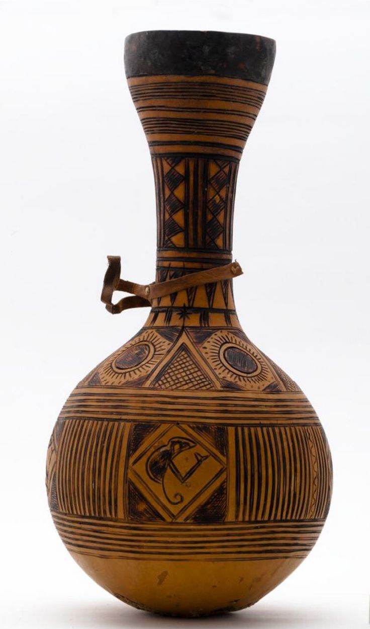 an old vase next to a ruler on a white background with black and brown designs