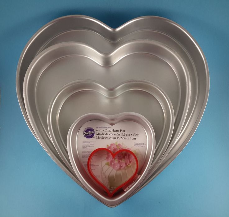 three heart shaped pans are arranged in the shape of a heart on a blue background