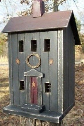 a bird house with a wreath on the top and star decorations on the roof, sitting on a tree stump