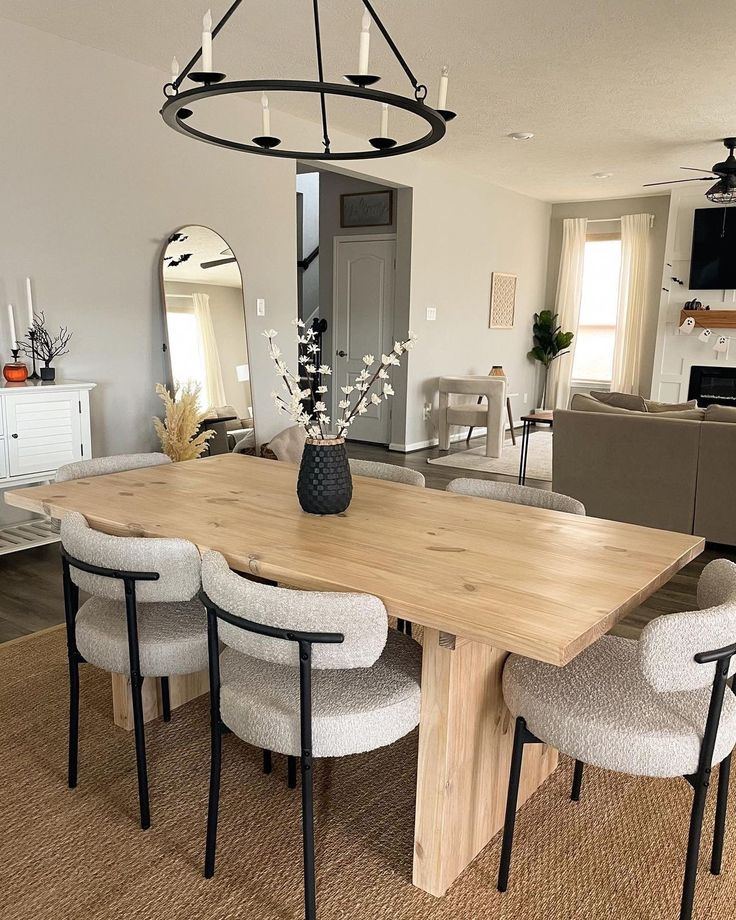 a dining room table with four chairs and a vase on top of it in front of a large mirror