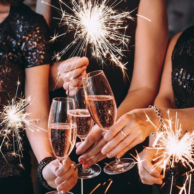 two women holding champagne flutes with sparklers in their hands