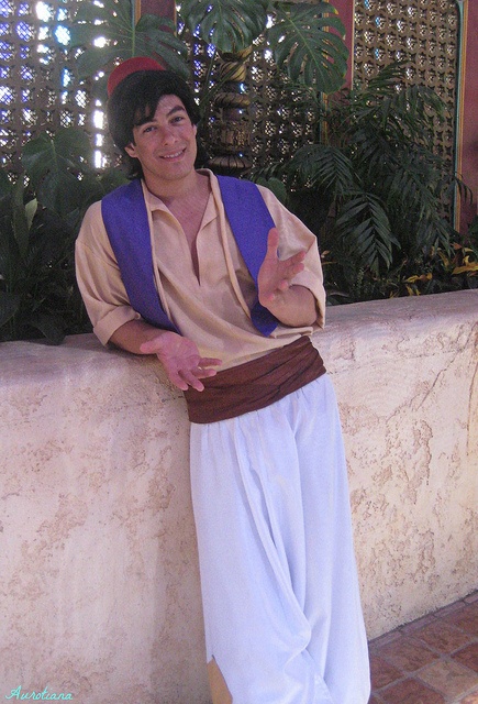 a man in costume leaning against a wall with his hand on his hip and smiling