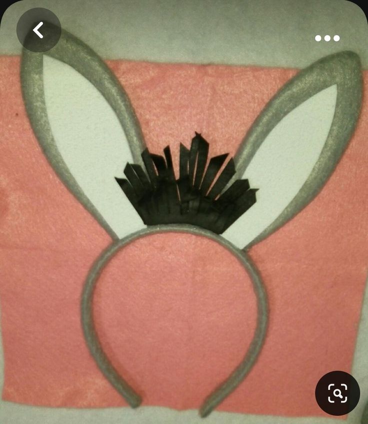 a bunny ears headband on top of a pink towel with white and black trim