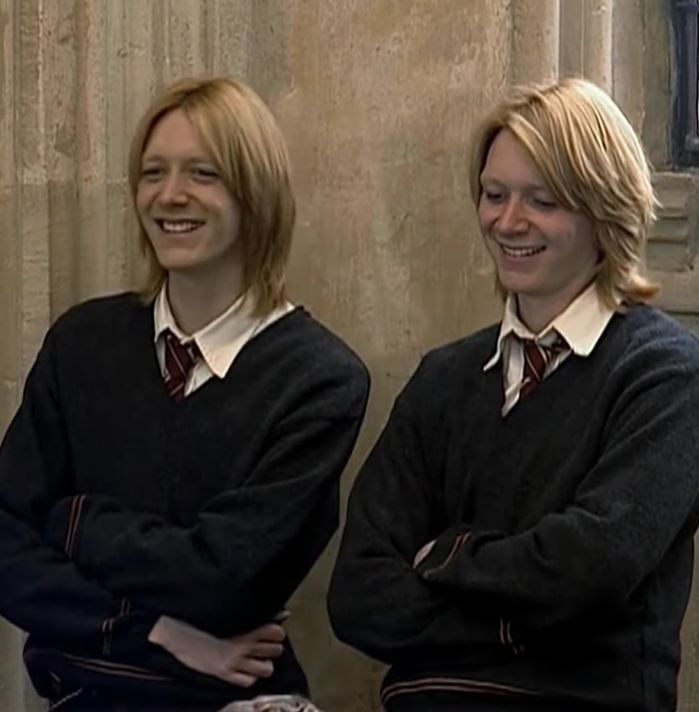 two women in black sweaters standing next to each other with their arms crossed and smiling